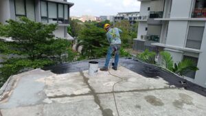 staff applying waterproofing bituminous primer on flat roof