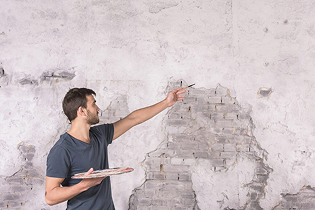 A waterproofing specialist inspecting a damaged wall to identify the root cause of water leakage during an initial on-site assessment.