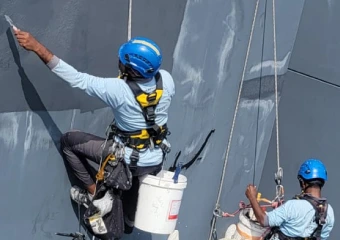 Waterproofing specialist team using professional rope access to apply external wall coatings on a tall building.