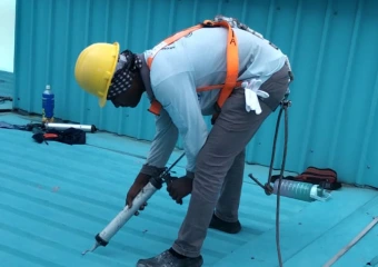 A waterproofing specialist applying sealant to a metal roof, offering expert roof waterproofing solutions to prevent leaks.