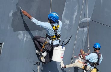 Waterproofing specialist team using professional rope access to apply external wall coatings on a tall building.